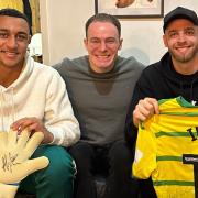 Canaries players Adam Idah, left, and Angus Gunn, right, with Chris Reeve of Talk Norwich City with items donated to a Big C charity raffle