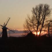 Norfolk at its alluring best with windmill, trees and moody skies combining for a sunset symphony