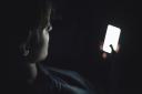 Teenage boy using smart phone in the dark. Photo: Getty Images/iStockphoto
