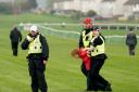 A member of activism group Animal Rising is restrained by police at the Scottish Grand National