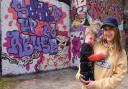 Megan Campbell, victim of domestic abuse, with her two-year-old son, Stanley, by the graffiti 'Stand Up To Abuse' she has painted highlighting Leeway, near Anglia Square. Picture: DENISE BRADLEY