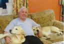 A spot of relaxation for retired headmaster Peter Woods at his North Walsham home  with canine chums Jess and Judy Image: SUPPLIED