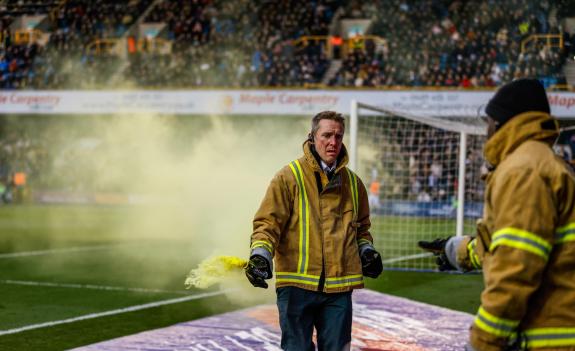 Norwich Evening News: A fire marshal removes a flare from the pitch after Gabriel Sara scored for the Canaries against Millwall Norwich Evening News: A fire marshal removes a flare from the pitch after Gabriel Sara scored for the Canaries against Millwall