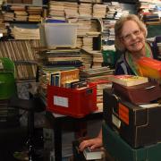 Jenny Newton, manager of the Oxfam Books and Music shop in Bedford Street, dwarfed by the piles of books they have been donated during lockdown. Picture: DENISE BRADLEY