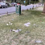 Rubbish left strewn across the green next to a bin in Bawburgh